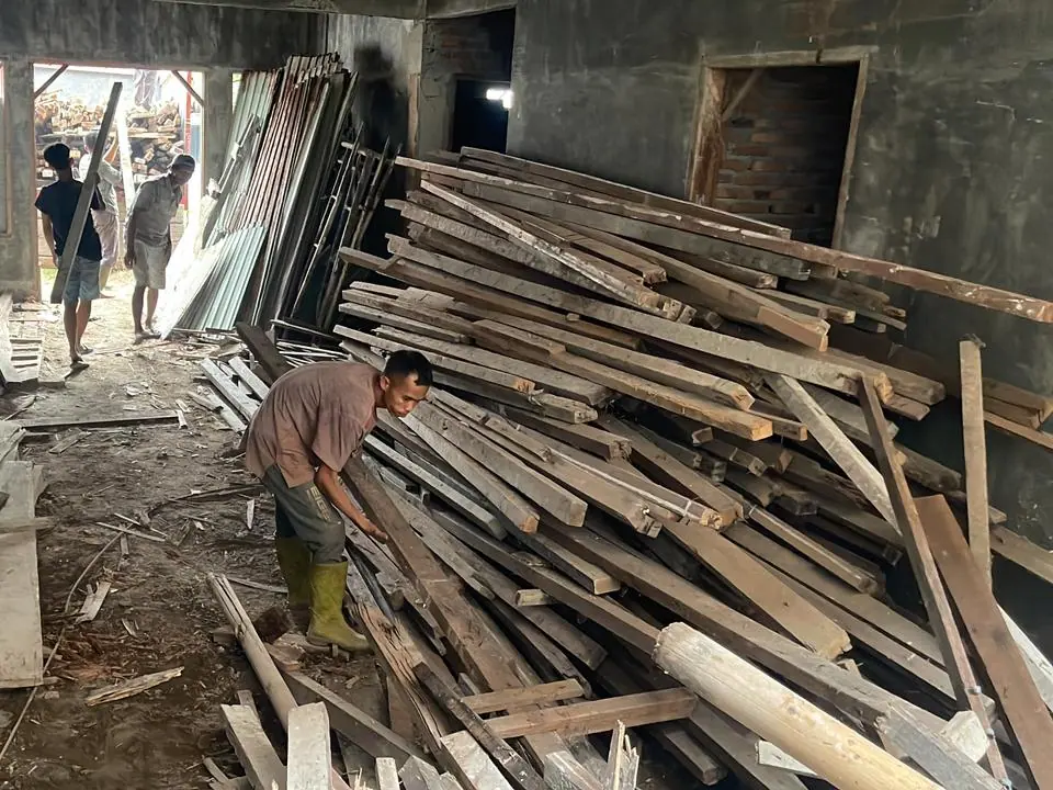 Pekerja memilah kayu hasil bongkaran di dalam bangunan yang sedang dibongkar